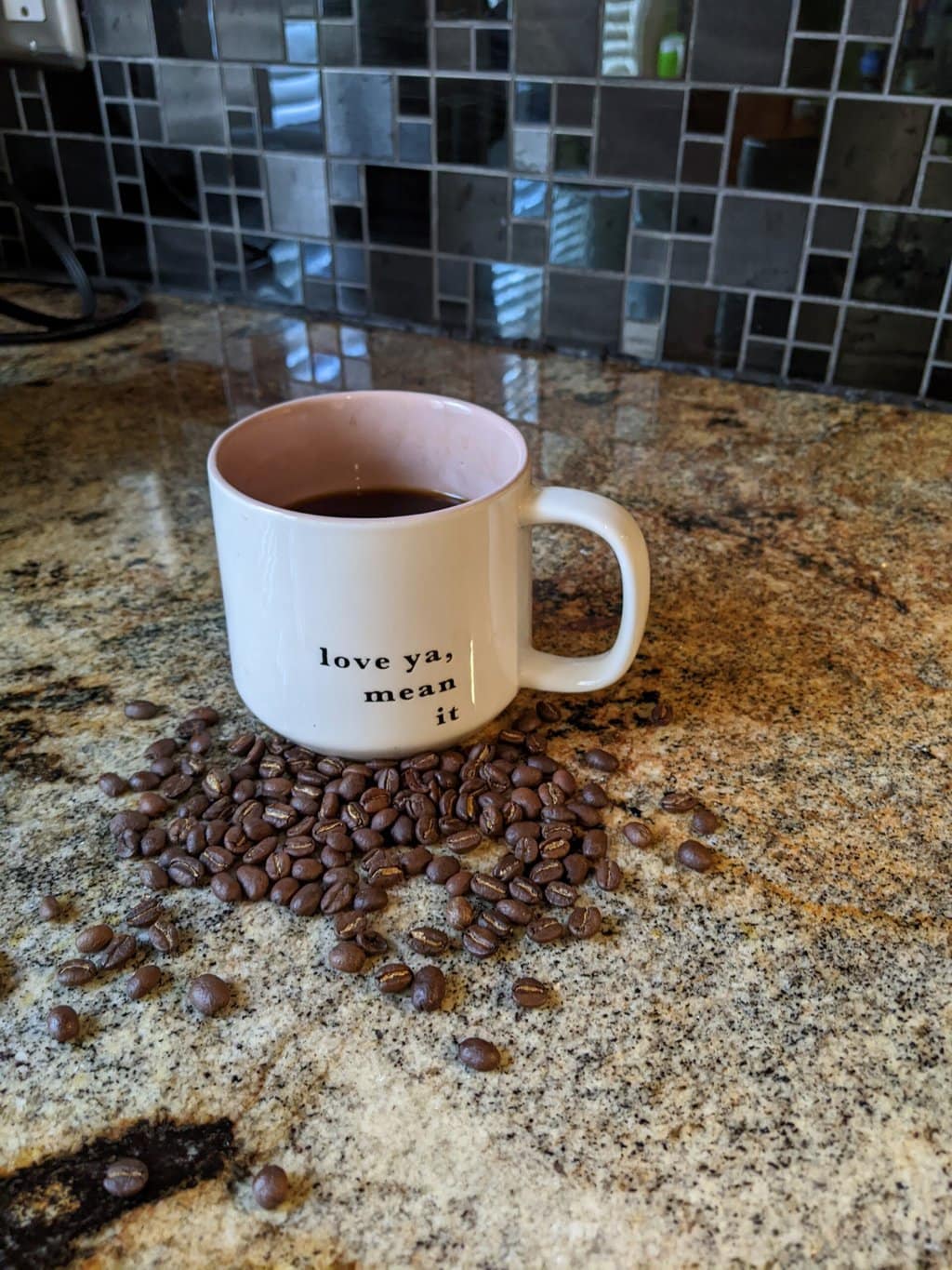 a cup of brewed Peace Coffee stands next to coffee beans on the kitchen table