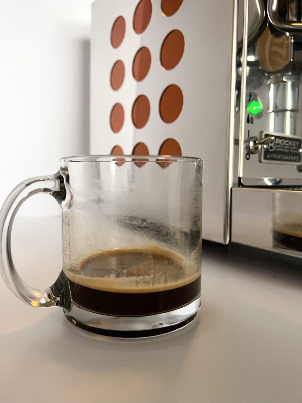 a cup of espresso against the background of the Rocket Espresso Appartamento coffee machine