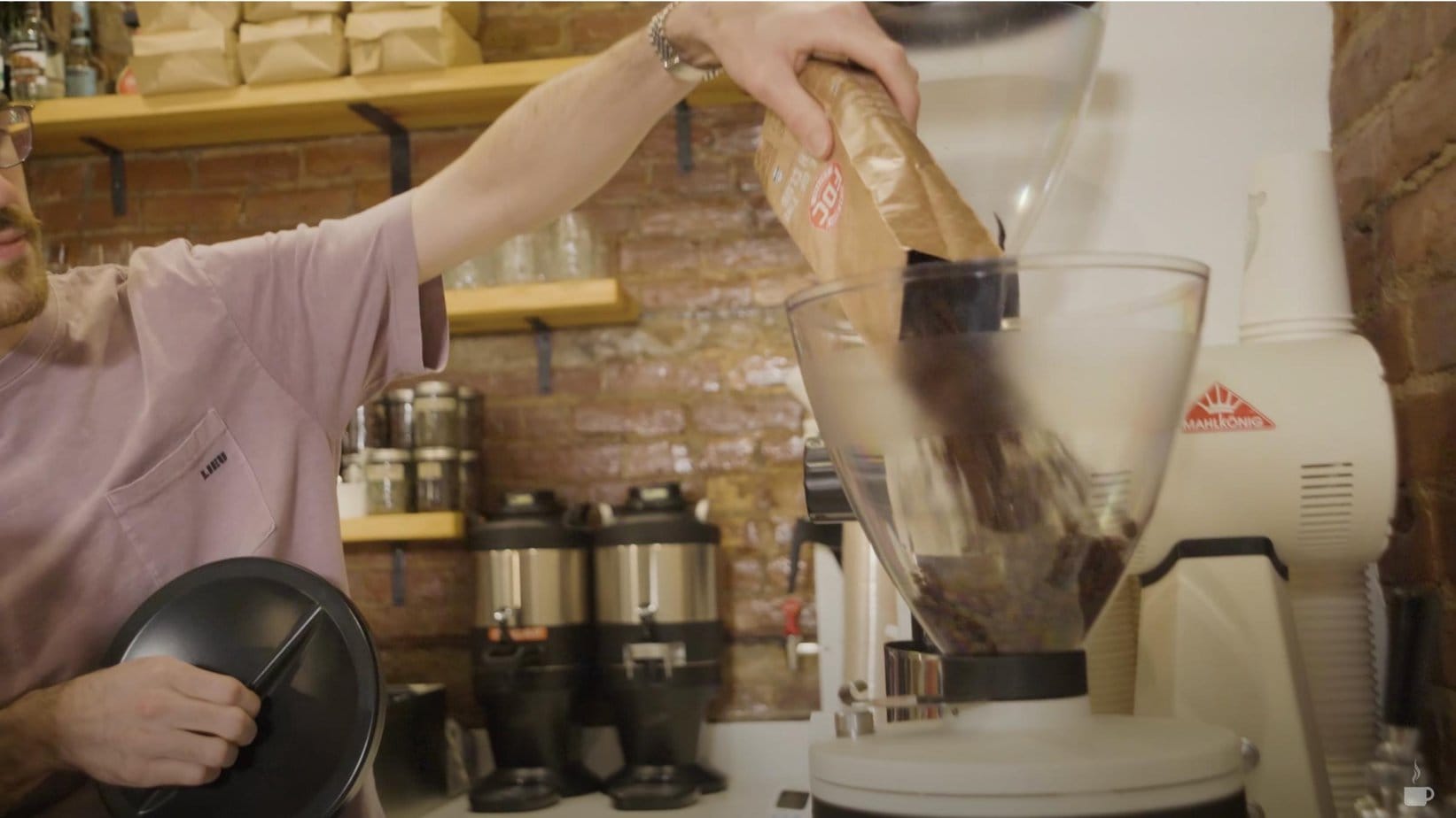 barista pours Fire Dept. Coffee beans into the grinder