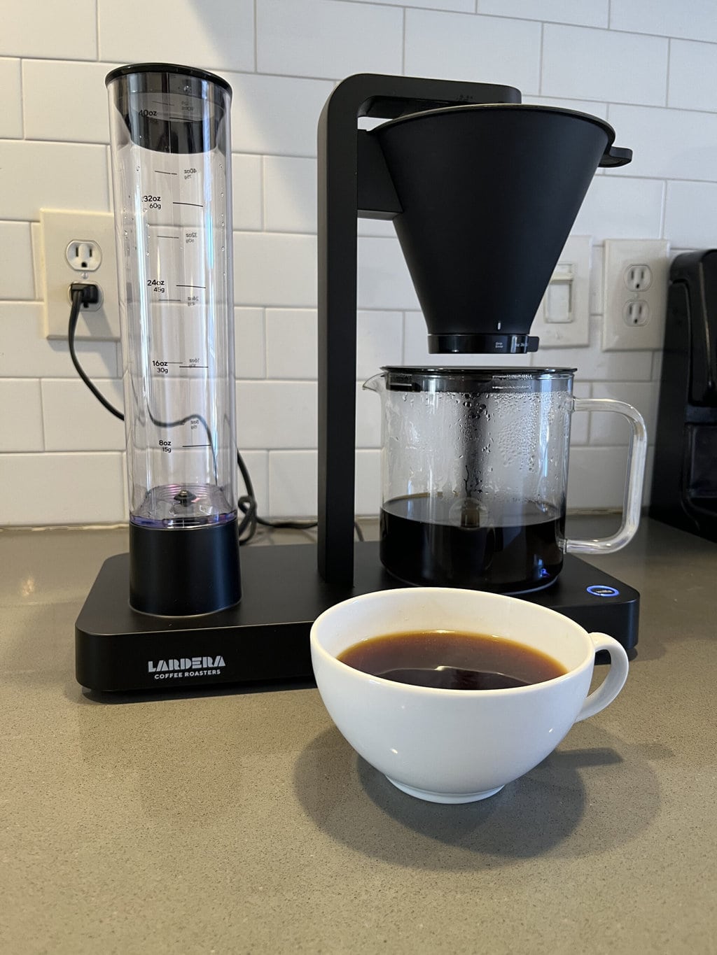 Wilfa Coffee Maker next to a white cup of espresso coffee
